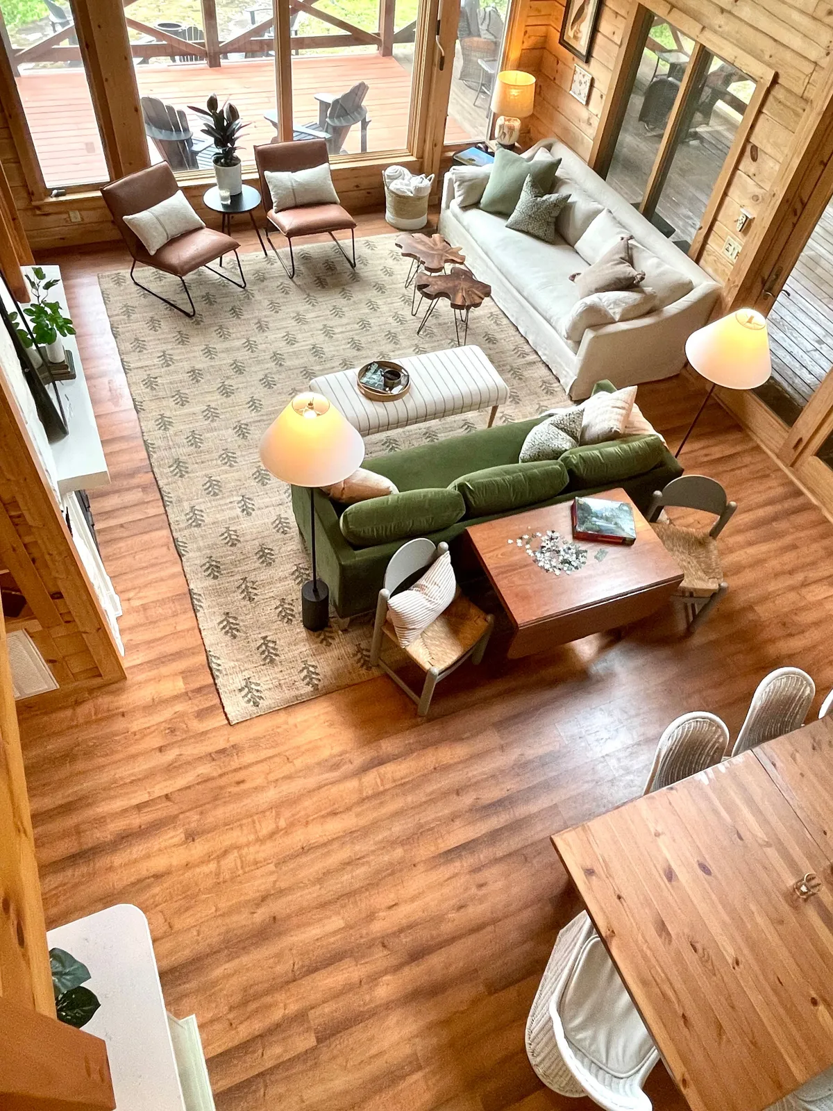 A welcoming lounge area with a green sofa, natural wooden table, large windows, and a textured rug. The layout encourages group gatherings, reading, or enjoying a quiet moment while natural light streams in, creating a peaceful, social atmosphere.
